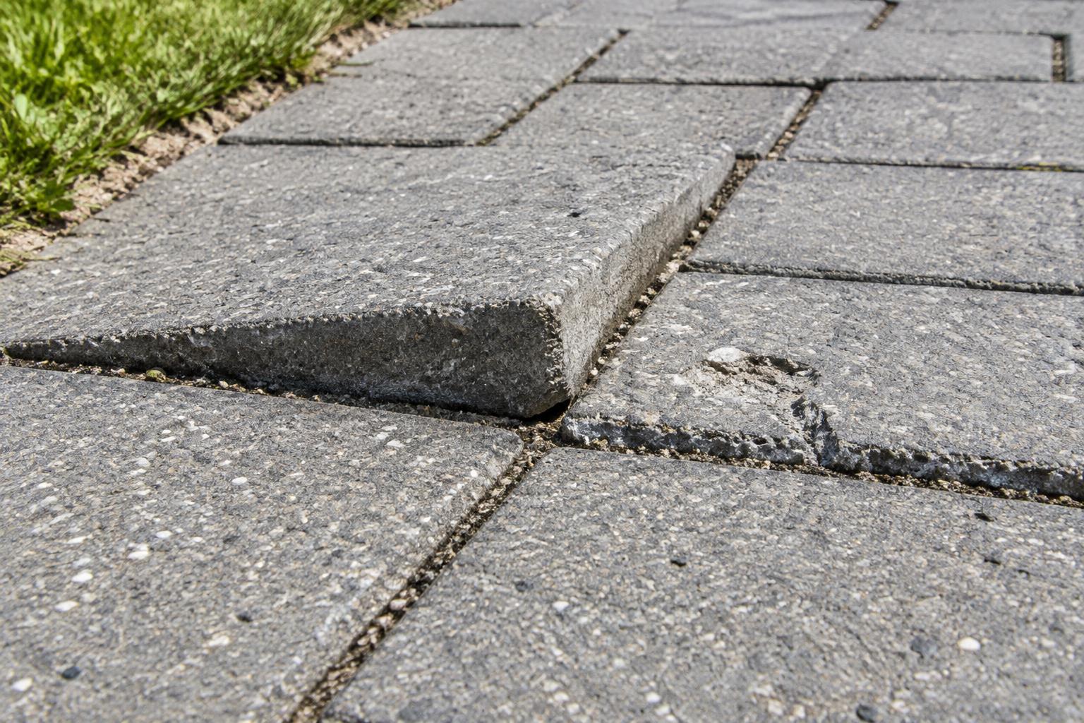 Paver Spalling illustration Raised edge and chipped surface on gray concrete walkway pavers